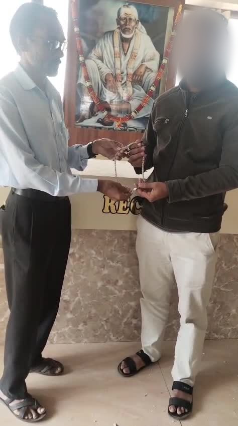 Hotel Saikrupa's reception manager handing back a silver chain to a guest at reception, guest's face blurred
